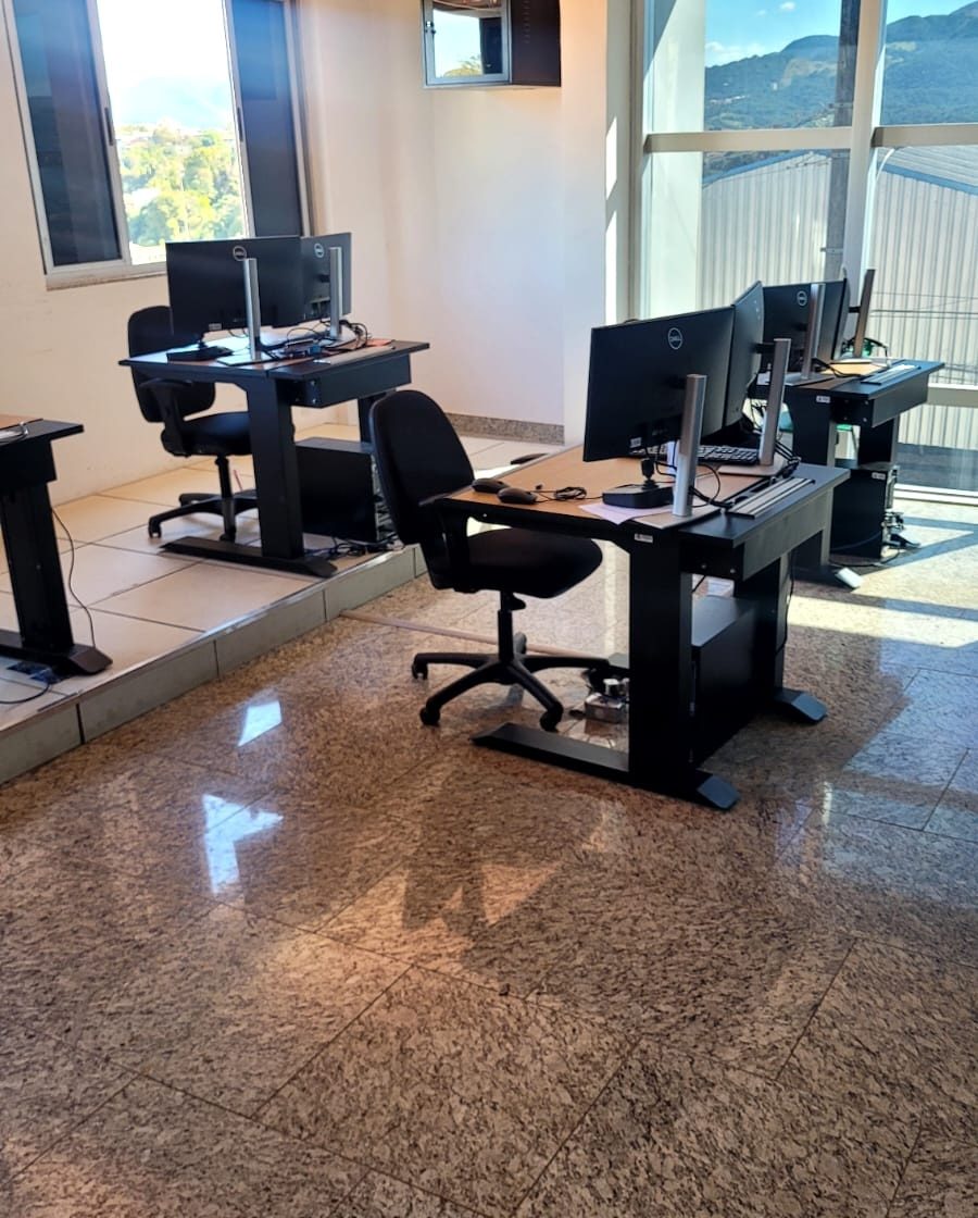 Sala de operação da central de monitoramento de Brumadinho (MG), com estações de trabalho e as montanhas vistas pela janela