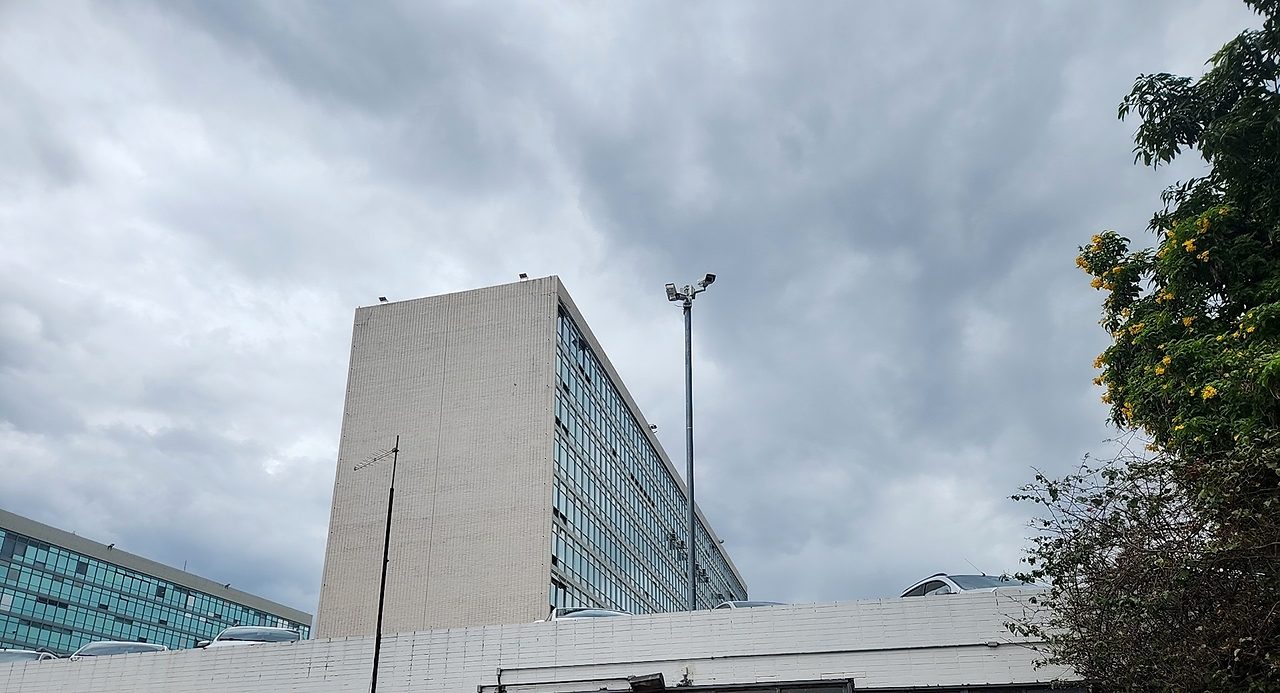 Prédio ministerial da Esplanada dos Ministérios e poste com câmeras sob céu nublado